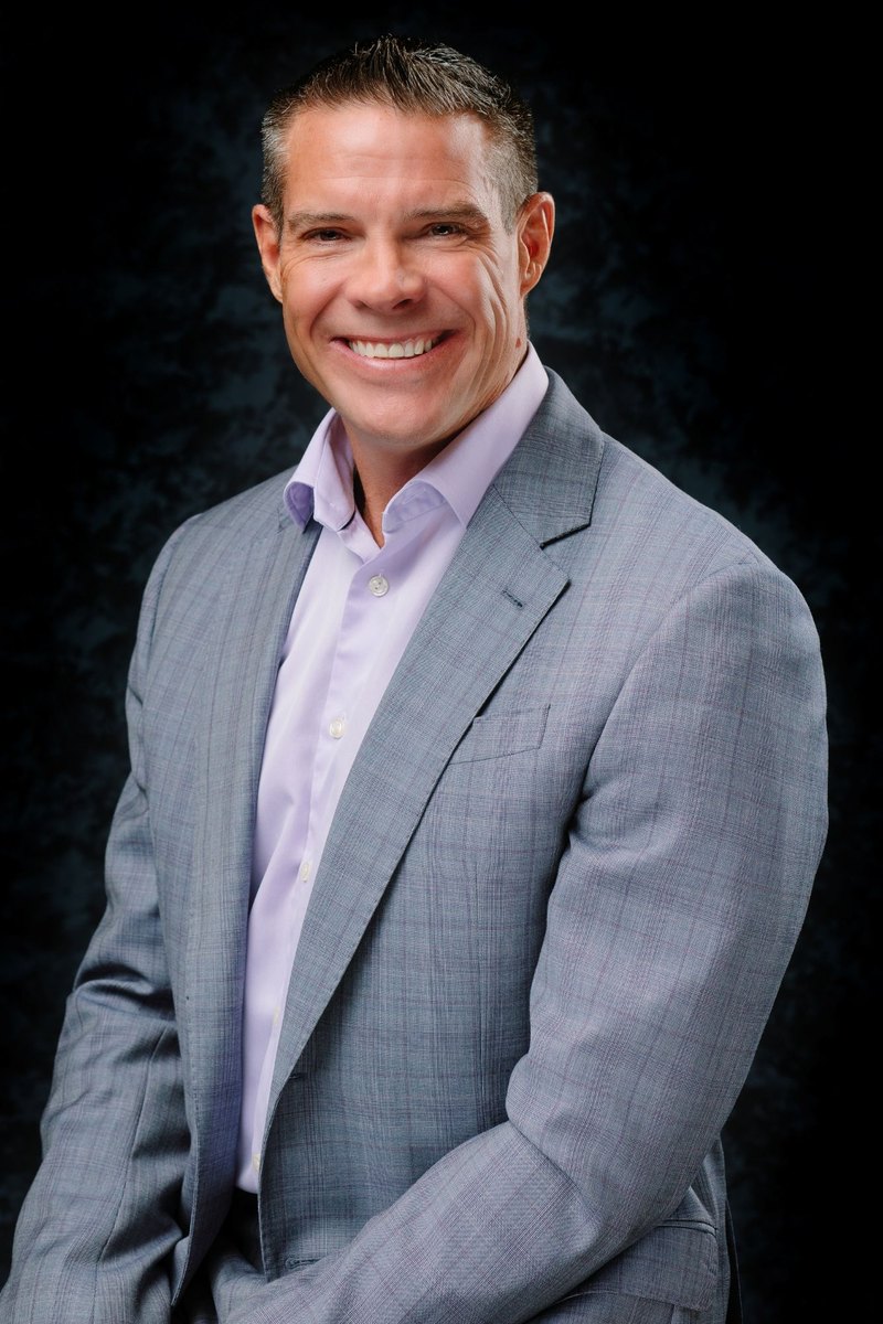 Bryan E. Burke, CPA, in a gray suit and lavender shirt
